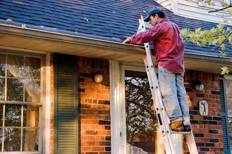 Man on Ladder Cleaning Gutter, Spring Home Maintenance, Checking Your Gutter System