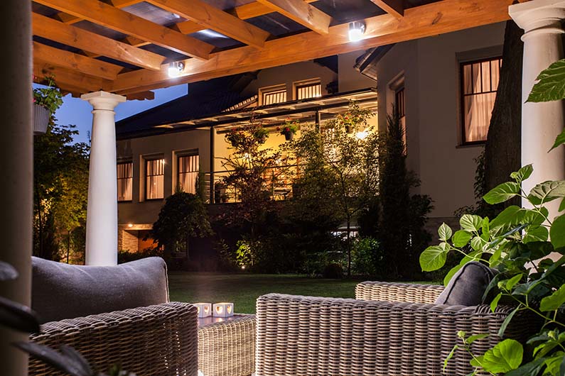 Backyard at night with pergola and furniture, outside garden