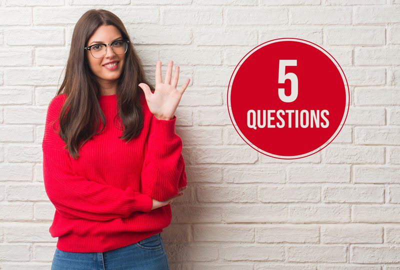 Woma in red shirt against beige wall, with a red circle on the wall, text says, "5 Questions".