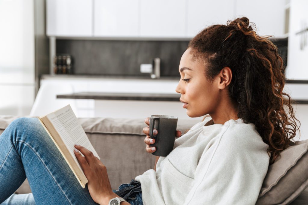 African American woman drinking tea and reading 7 Ways to Find Your First Home