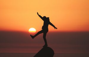 mental health, depression, how to over come depression, person balanced on a rock with sunset in the background